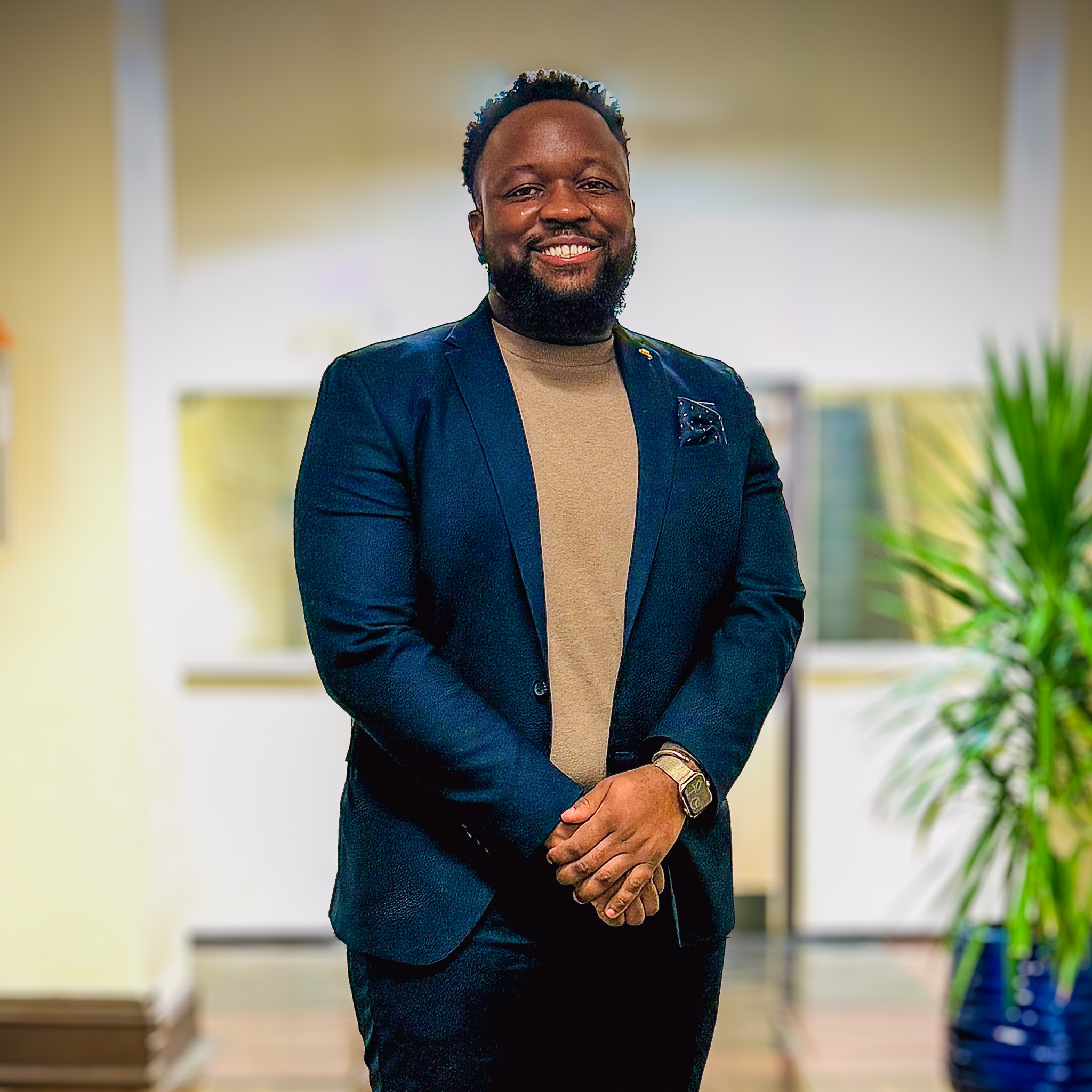 Dr. Kenneth Glover, Principal of Overbrook Elementary School, standing indoors wearing a navy suit and tan shirt, smiling confidently.
